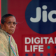 A woman waits at a bus stop with an advertisement of Reliance Industries' Jio telecoms unit in Mumbai